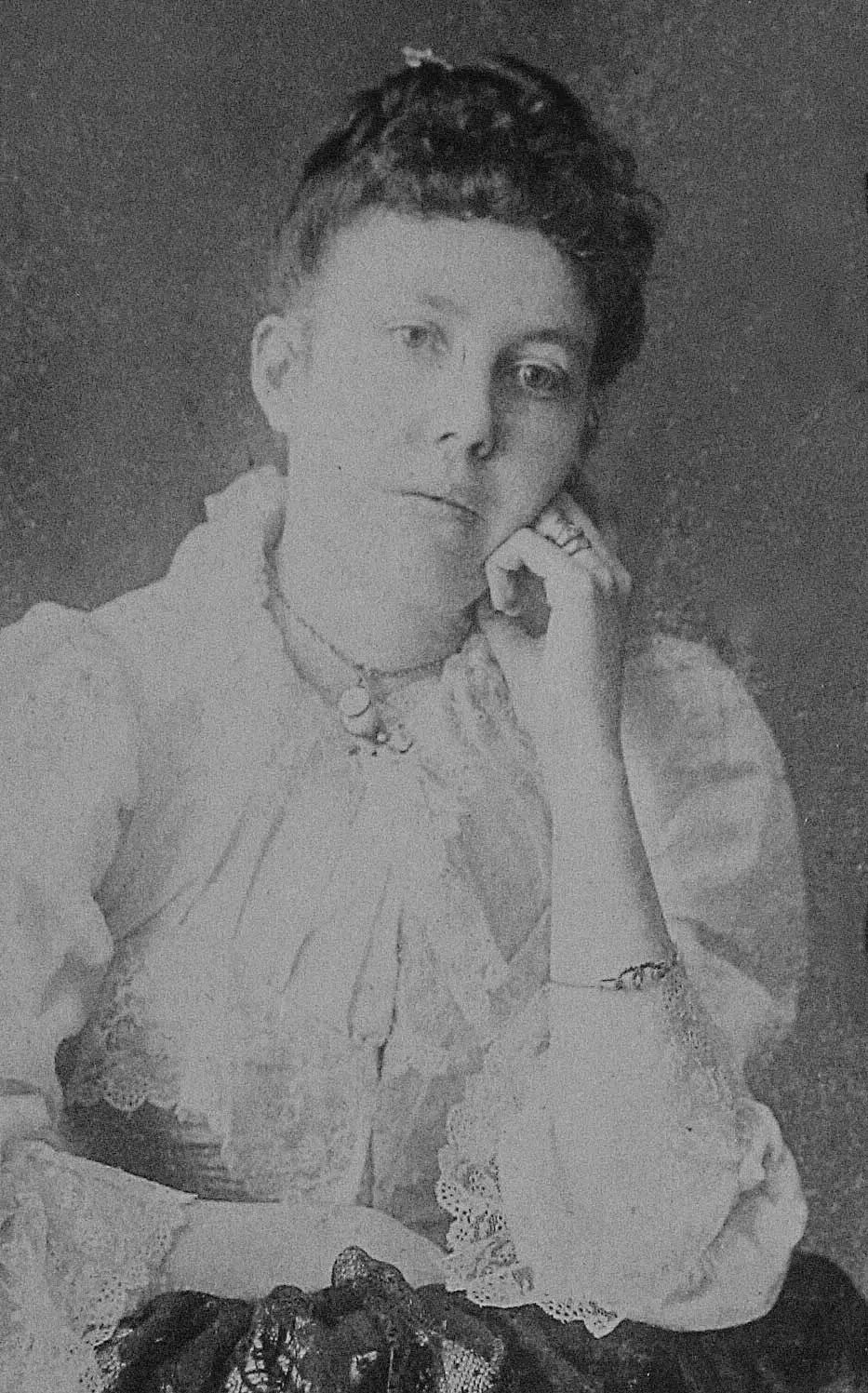 Image d’une jeune femme aux cheveux foncés et avec le menton qui repose sur sa main.
