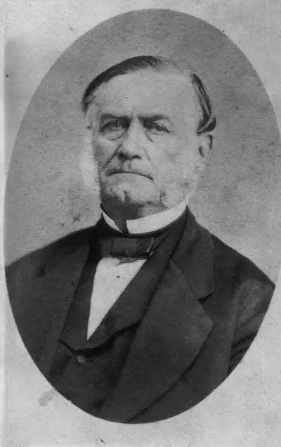 black and white photo of a man with graying sideburns and a black suit