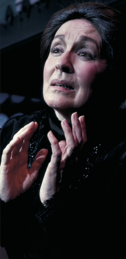 a close up of a woman's face, with hands poised near her chin