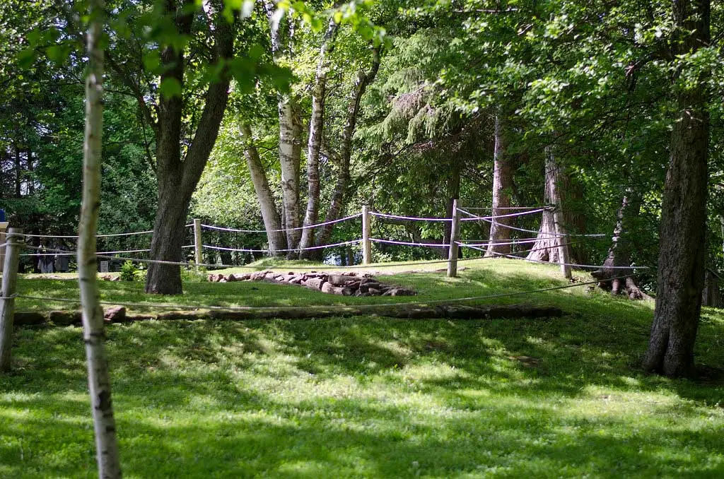 Une clôture de corde entoure une fondation de grès rouge dans les bois.