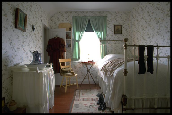 photo de la chambre d’une fille ensoleillée avec de la literie de couleur pâle et une petite chandelle à la fenêtre