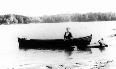 Image en noir et blanc d’une femme dans un canot sur un lac tranquille.