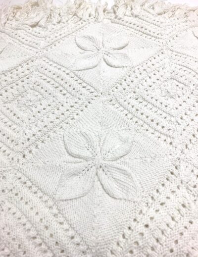 detail of a bedspread made of different knitted squares sewn together some with geometric shapes and some with leaves