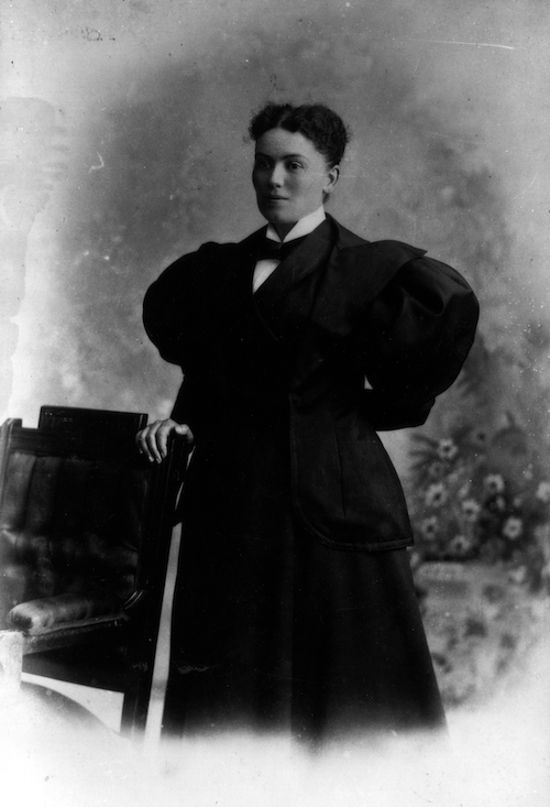 photo en noir et blanc d’une femme qui ne sourit pas et qui porte une robe avec d’immenses manches bouffantes